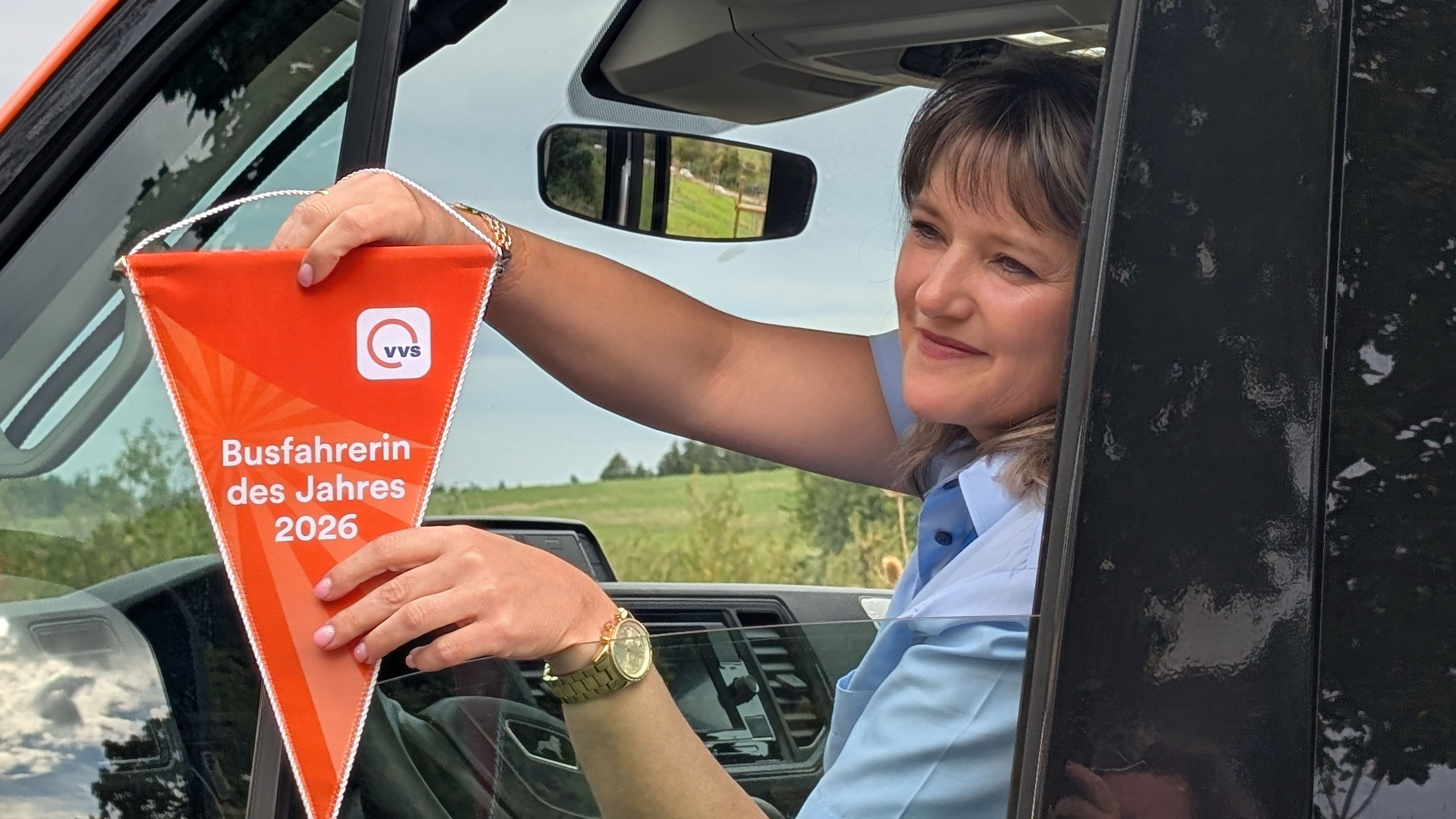 Die Busfahrerin des Jahres am Steuer mit Wimpel in der Hand